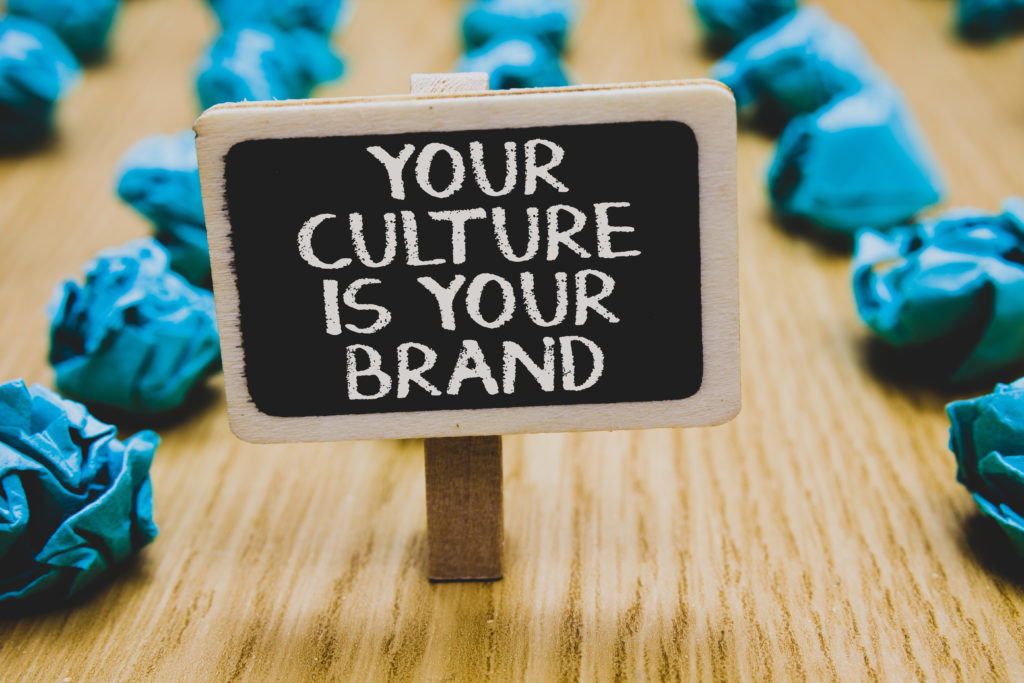 Handwriting text writing Your Culture Is Your Brand. Concept meaning Knowledge Experiences are a presentation card Stand blackboard with white words behind blurry blue paper lobs woody floor